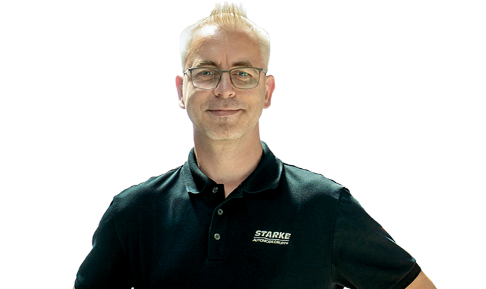 Ein älterer Mann mit hellem Haar trägt ein schwarzes STARKE Polo-Shirt.