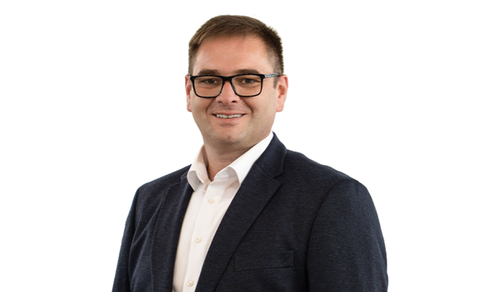 Ein Mann mittleren Alters mit braunem Haar trägt Brille und einen Anzug.
