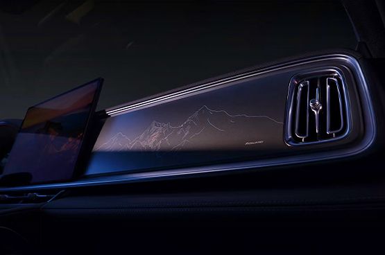 Ausschnitt aus dem Innenraum des Geely Monjaro EM-i mit Zentraldisplay, beleuchtetem Armaturenbrett mit Bergmotiv und Lüftungsdüse.