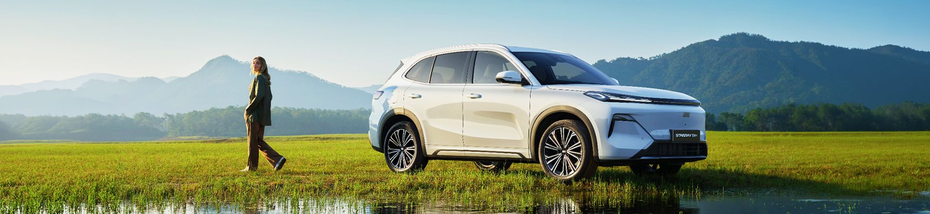 Geely Starray EM-i in Weiß in einer weiten Naturkulisse mit Bergen und Wiese im Hintergrund.