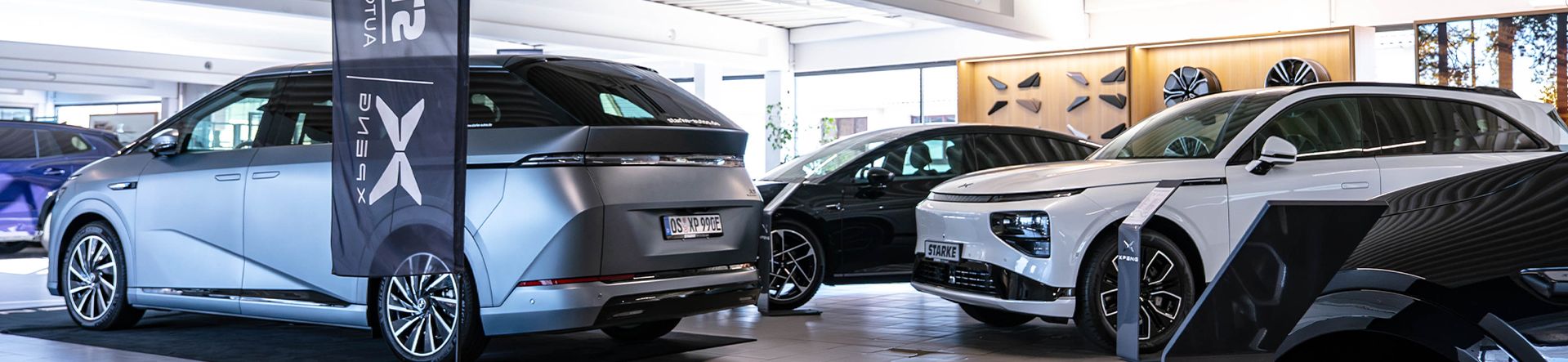 Mehrere XPENG Modelle im STARKE Showroom: Grauer X9 Van, schwarzer P7 und weißer G6 SUV, dazwischen eine STARKE Automobilgruppe XPENG Flagge.