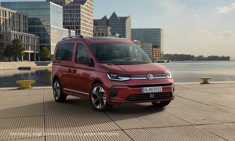 Ein roter Caddy Life vor einem Hintergrund, der an eine moderne Stadt am Wasser erinnert.