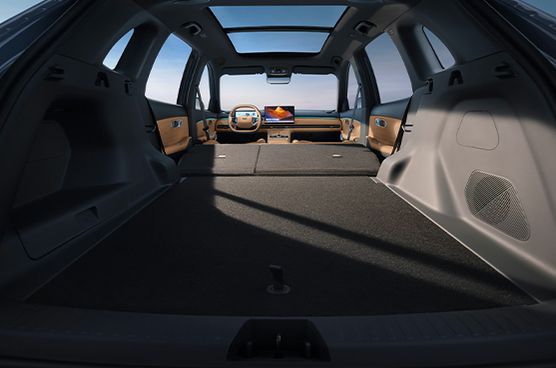 Großer Kofferraum des Geely Starray EM-i mit vollständig umgeklappter Rücksitzbank, ebener Ladefläche und Blick nach vorn ins Cockpit mit HD-Zentraldisplay.