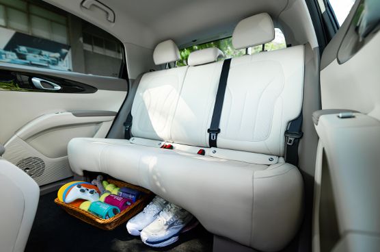 Rücksitzbereich des Geely E2 mit heller Innenausstattung sowie Ablagekorb und Schuhen im Fußraum.