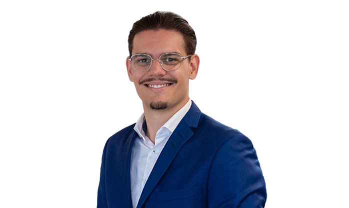 Ein junger Mann mit schwarzem Haar trägt eine Brille und einen Anzug.