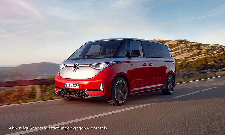 Ein zweifarbiger VW ID.Buzz (oben silbern, unten rot) fährt auf einer Landstraße. Im Hintergrund sieht man eine bergige Landschaft vorbeiziehen. Unten links im Bild steht der Hinweis: " Abb. zeigt Sonderausstattungen gegen Mehrpreis".