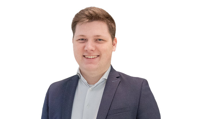 Portrait eines Mitarbeiters mit kurzem Haar im weißen Hemd mit schwarzem Jackett.