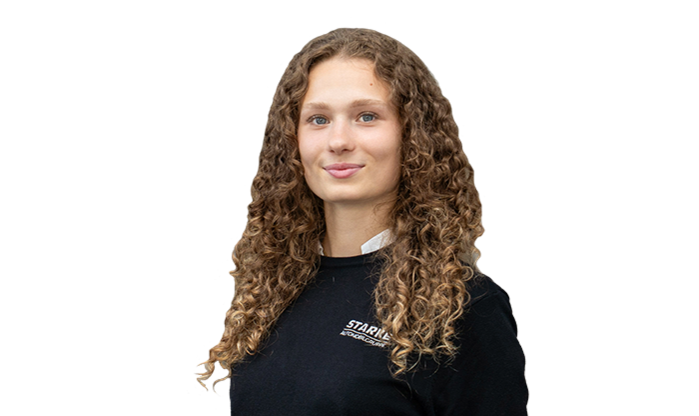 Eine junge Frau mit braunem, lockigem Haar trägt einen schwarzen STARKE Pullover.