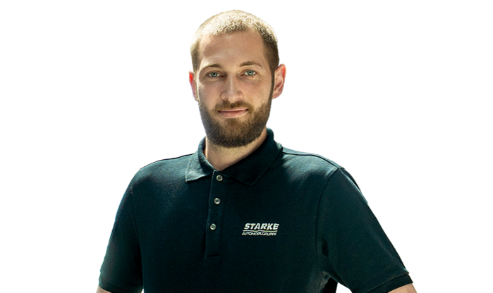 Ein junger Mann mit blondem Haar trägt ein schwarzes STARKE Polo-Shirt..