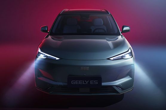 Frontansicht des Geely E5 in dunklem Grau mit eingeschalteten LED-Scheinwerfern, schmalem Tagfahrlicht, beleuchtetem Geely-Logo und Kennzeichen GEELY E5 vor rot-blauem Lichthintergrund.