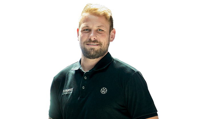 Ein junger Mann mit blondem Haar trägt ein schwarzes STARKE Polo-Shirt.