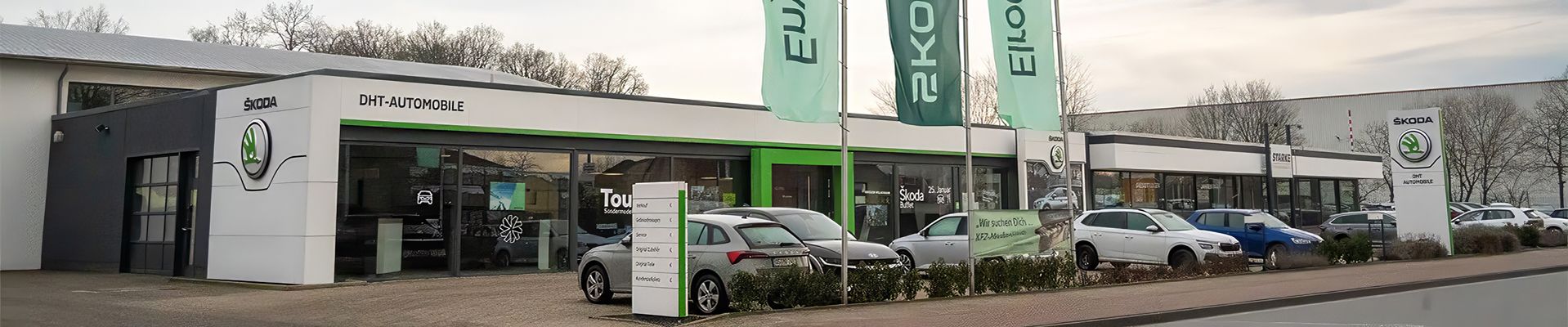 Auf dem Bild ist der DHT Automobile Standort der STARKE Automobilgruppe an der Niedersachsenstraße in Georgsmarienhütte. Im Vordergrund wehen Skoda Fahnen. 