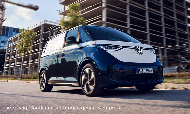 Ein zweifarbiger VW ID.Buzz Cargo (oben weiß, unten schwarz) fährt in der Stadt. Das Fahrzeug ist frontal und seitlich auf der Straße zu sehen. Im Hintergrund sieht man Gebäude, welche sich im Bau befinden sowie einen Kran. Unten links im Bild steht der Hinweis: "Abb. zeigt Sonderausstattungen gegen Mehrpreis".