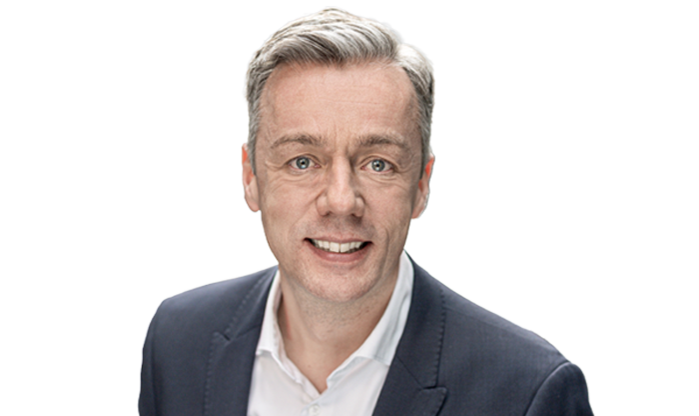 Ein Mann mit weißem Hemd, dunklem Sakko und grauen kurzen Haaren.