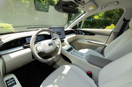 Heller Innenraum des Geely E2 mit hellem Lenkrad, digitalen Anzeigen und weißen Sitzen.