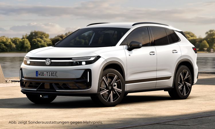 Weißer Volkswagen Tiguan in Frontseitenansicht auf einer befestigten Fläche vor einem Gewässer und bewaldetem Hintergrund.