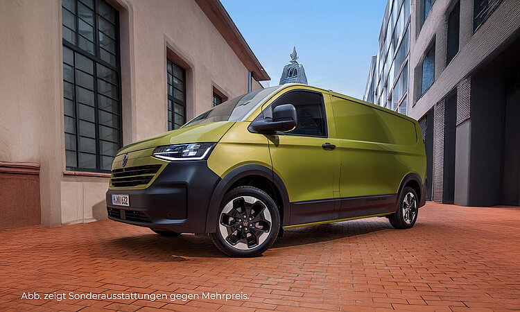 Ein gelber VW New Transporter steht auf einer rot gepflasterten Fläche, zwischen zwei Gebäuden. Das Fahrzeug ist seitlich und teilweise frontal zu sehen. Im Hintergrund sieht man eine Turmspitze. Unten links im Bild steht der Hinweis: "Abb. zeigt Sonderausstattungen gegen Mehrpreis".