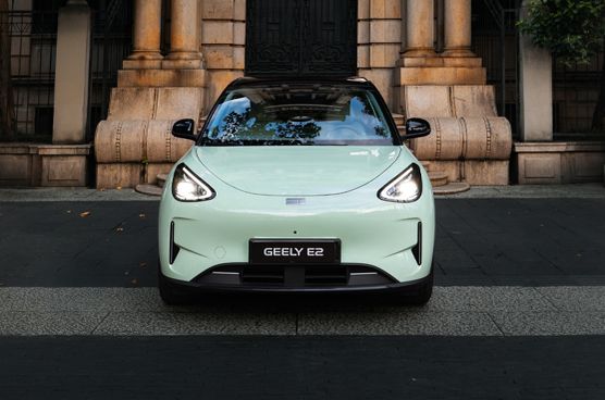 Geely E2 in Frontansicht vor einem Gebäude mit Natursteinfassade, Säulen und Treppenaufgang.