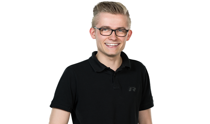 Portrait eines Mitarbeiters mit kurzem Haar und Brille in einem schwarzen Poloshirt.
