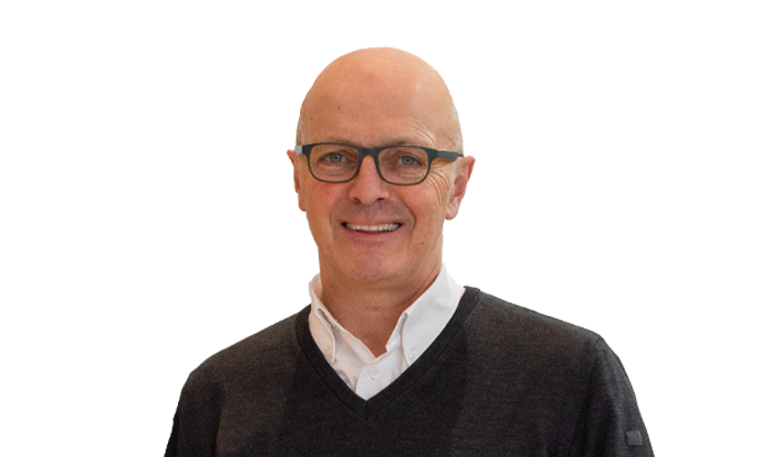 Portrait eines Mitarbeiters mit Brille in einem schwarzen Pullover mit weißem Hemdkragen.