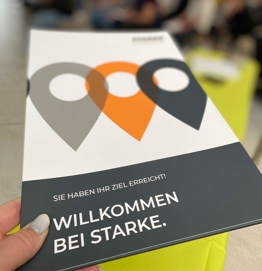 Dieses Bild zeigt eine grau - orange - weiße Mappe mit dem Slogan: WILLKOMMEN BEI STARKE. 