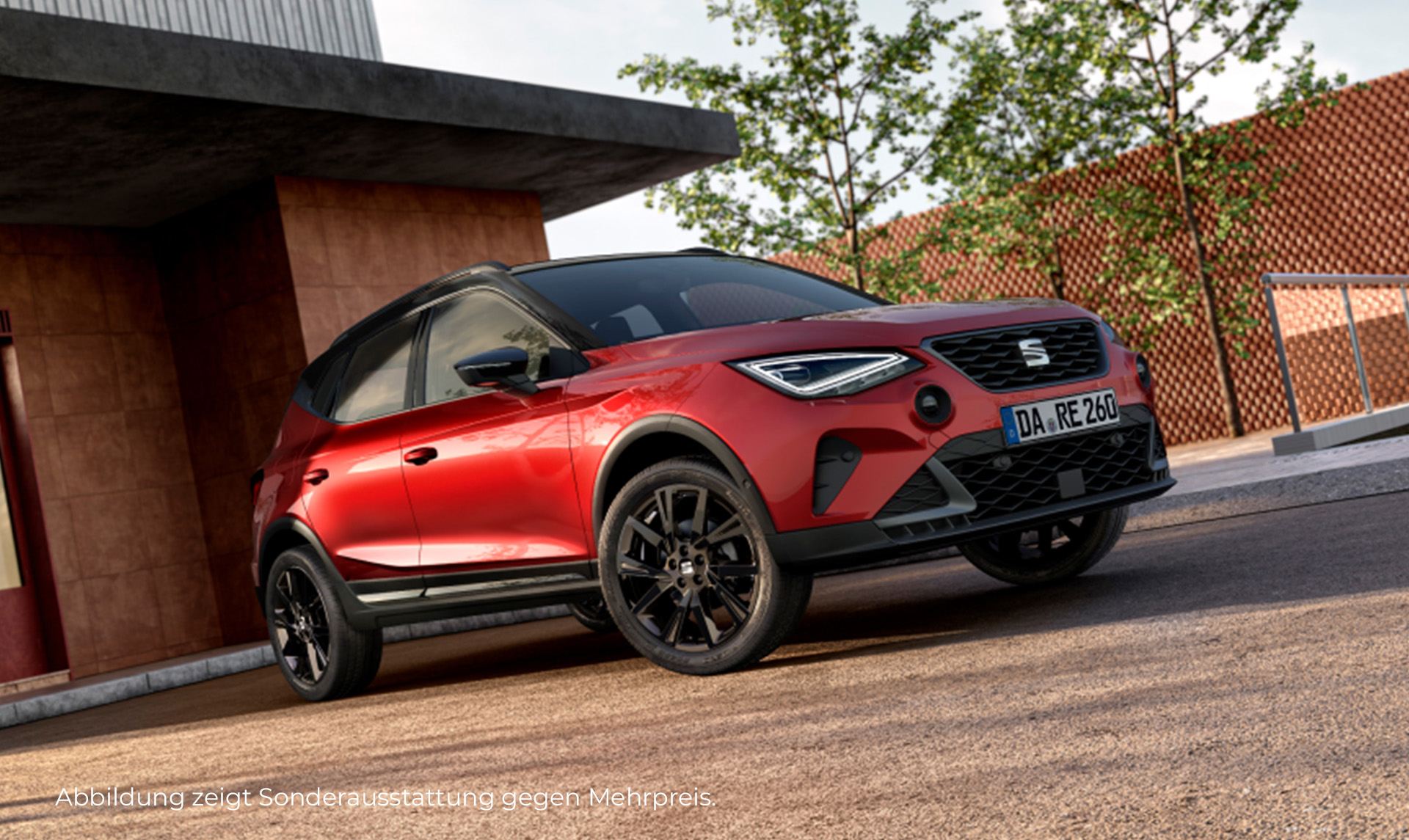 Auf dem Bild ist ein roter SEAT Arona in der Black Edition. Er ist rückwärts vor einem modernen Gebäude geparkt.