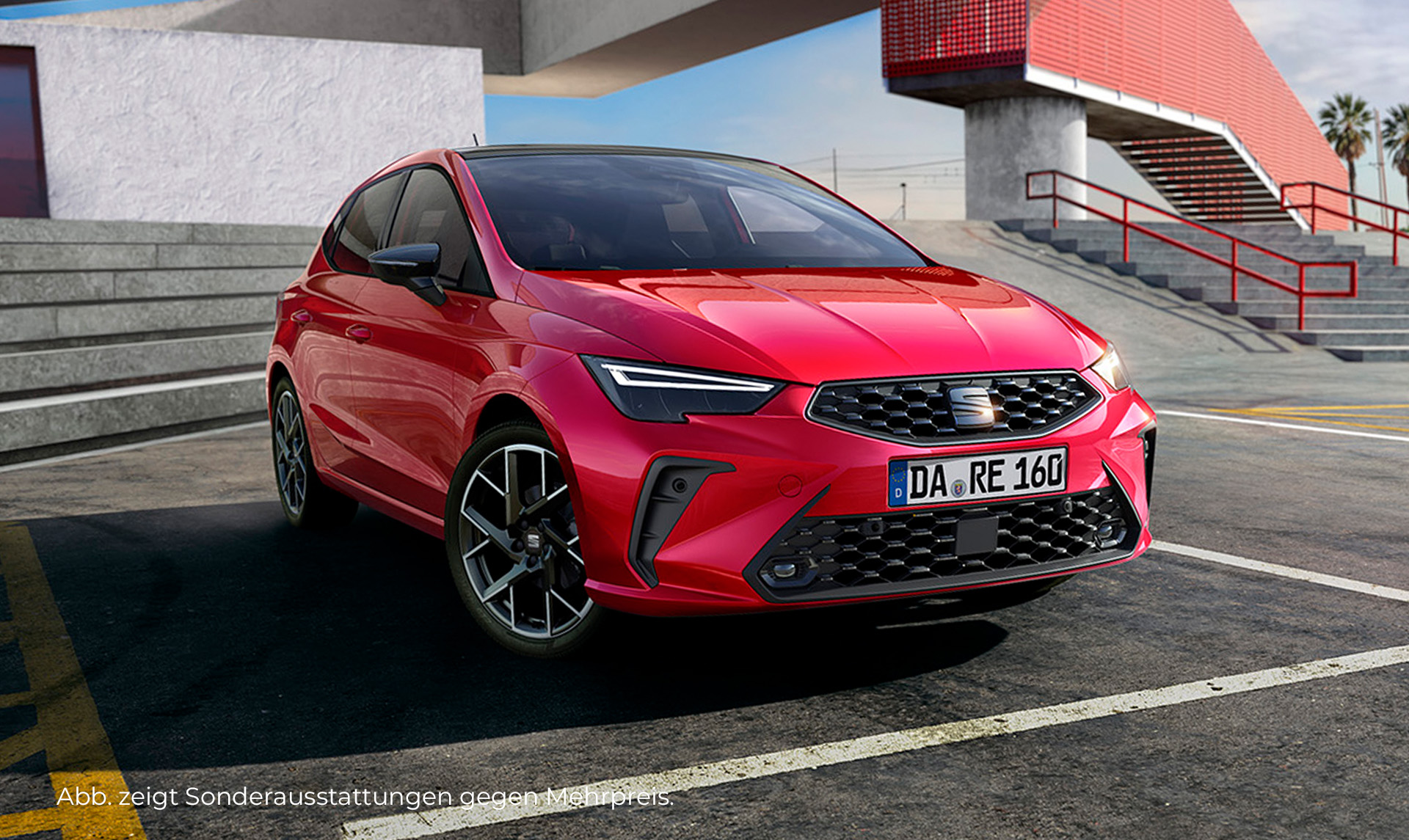 Ein roter SEAT Ibiza parkt auf der Straße in Fahrtrichtung rechts. Im Hintergrund ist eine graue Mauer und ein rotes Gebäude.