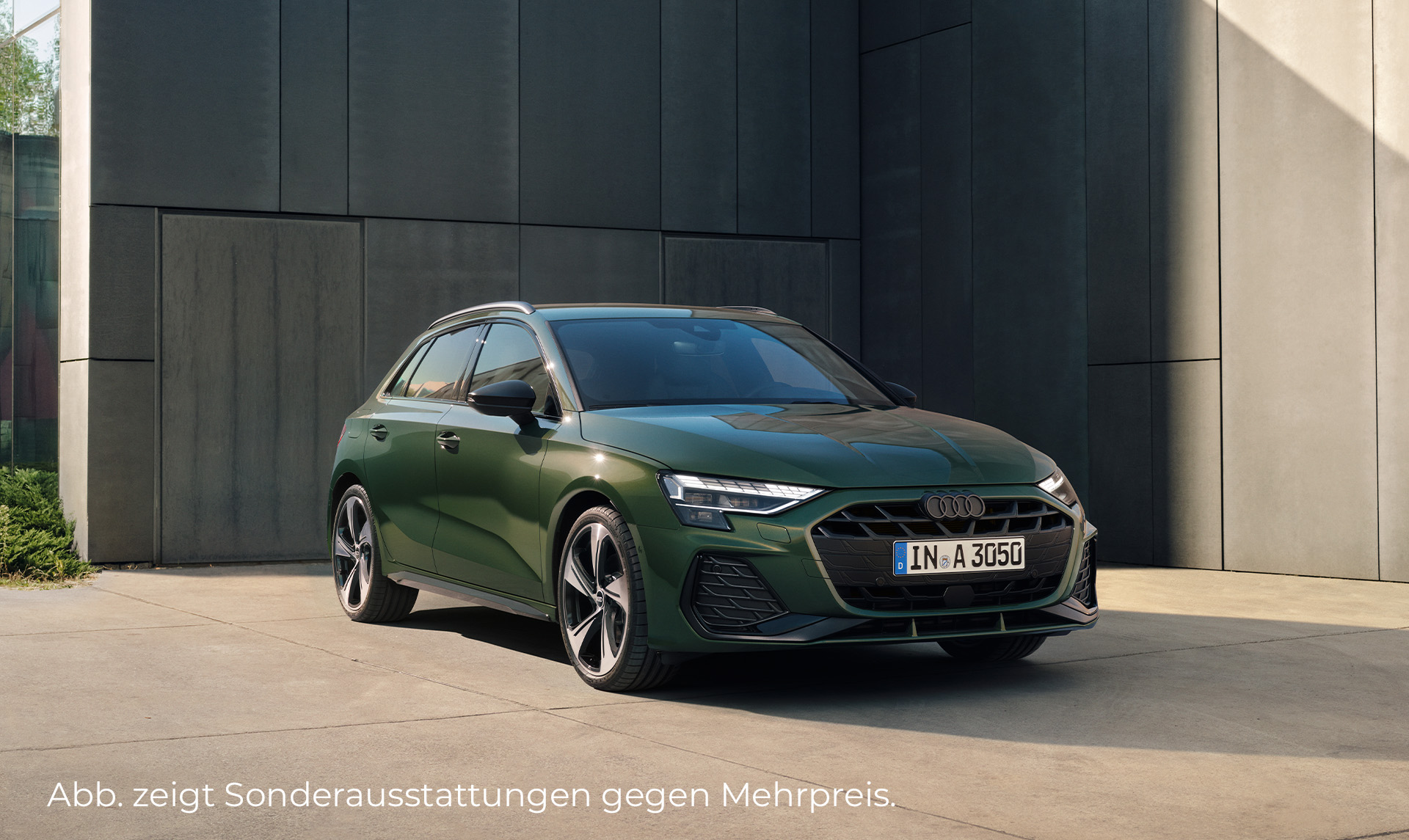 Das Bild zeigt einen grünen Audi A3 der vor einer schwarzen Wand steht. Zu sehen ist die Front und die linke Fahrzeugseite.
