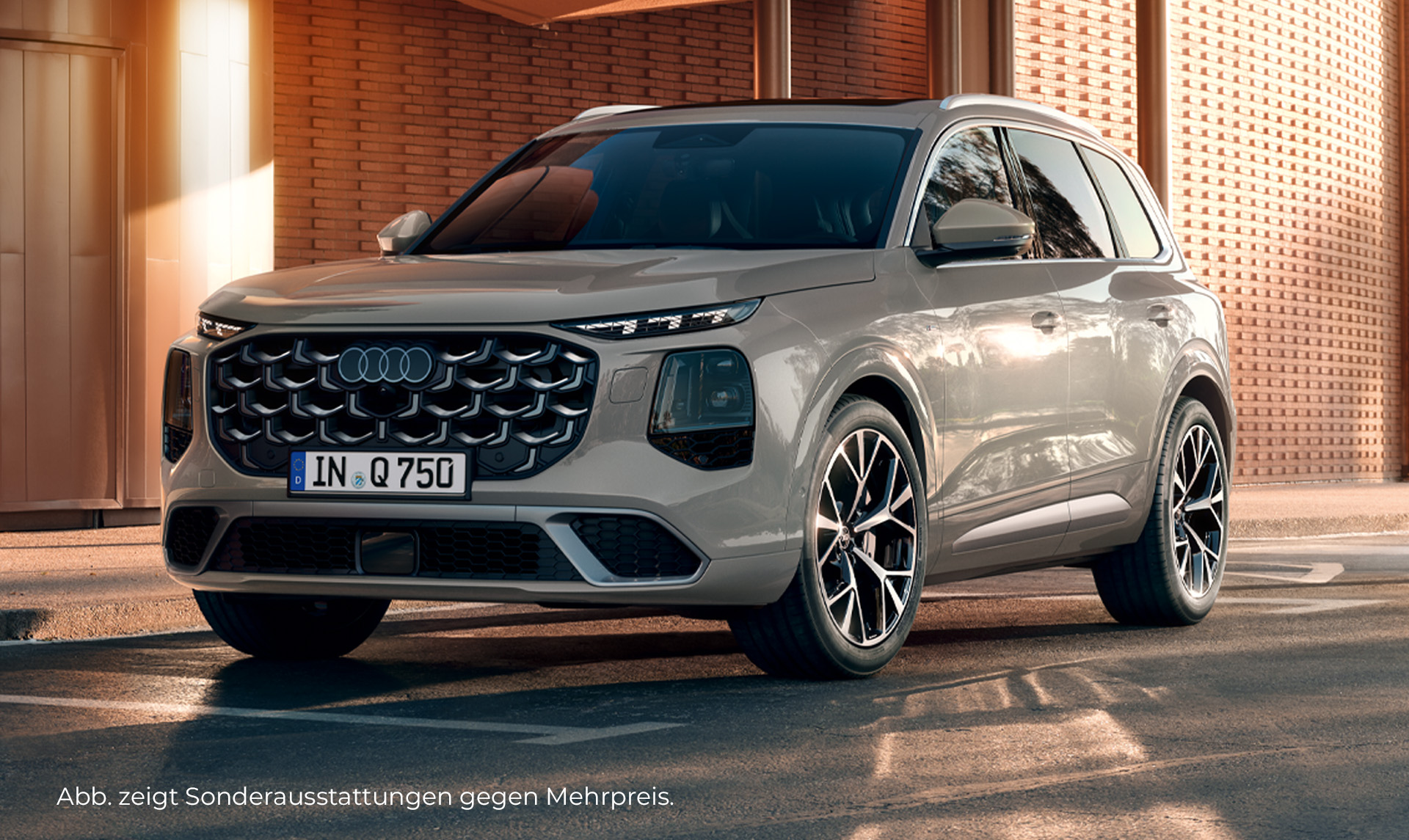 Audi Q7 in Frontseitenansicht vor einem Gebäude mit Backsteinfassade und großen Fensterflächen.