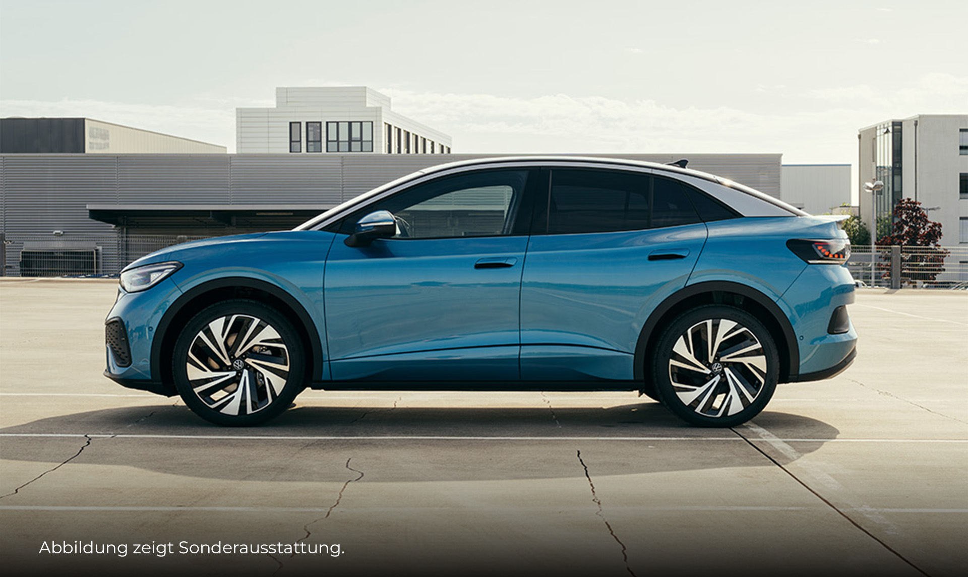 Ein blauer VW ID.5 steht seitlich auf einem großen Platz. Im Hintergrund sieht man moderne Gebäude. Unten links im Bild steht der Hinweis: "Abbildung zeigt Sonderausstattung".