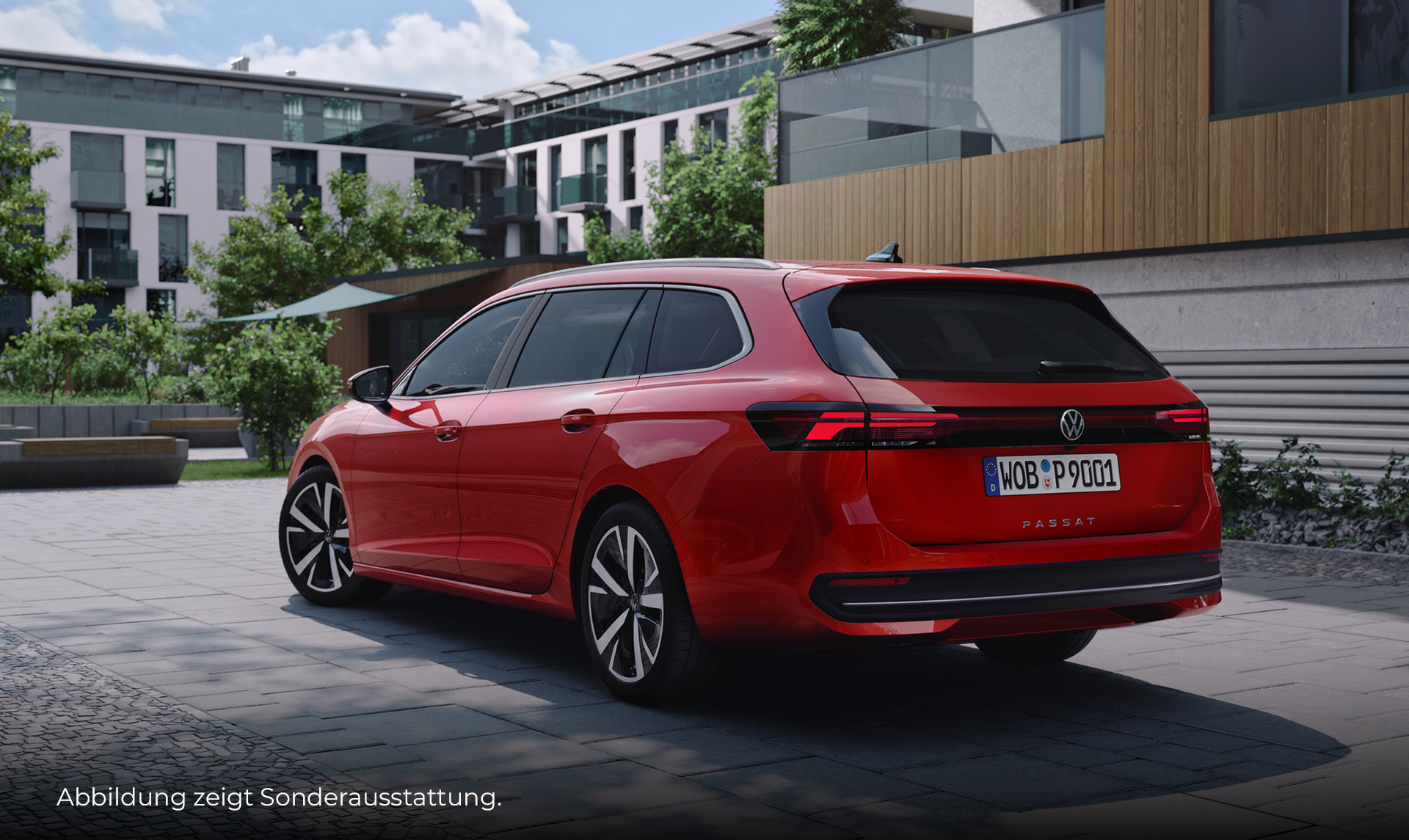 Ein roter VW Passat Variant steht auf einem gepflasterten Platz vor einem modernen Wohngebäude mit Holz- und Glasfassade. Das Fahrzeug ist von hinten und schräg seitlich zu sehen. Unten links im Bild steht der Hinweis: "Abbildung zeigt Sonderausstattung".