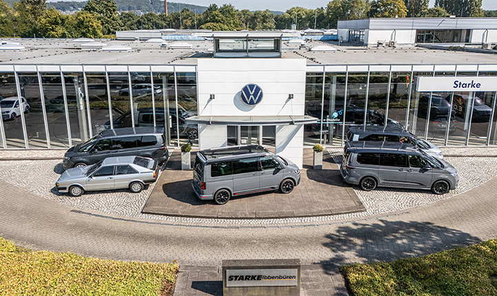 Auf dem Bild ist der STARKE Ibbenbüren Standort aus der Vogelperspektive zu sehen. Der Eingang des Gebäudes mit Volkswagen Logo ist in der Mitte der Aufnahme. Vor der Tür stehen mehrere Volkswagen Multivan. 