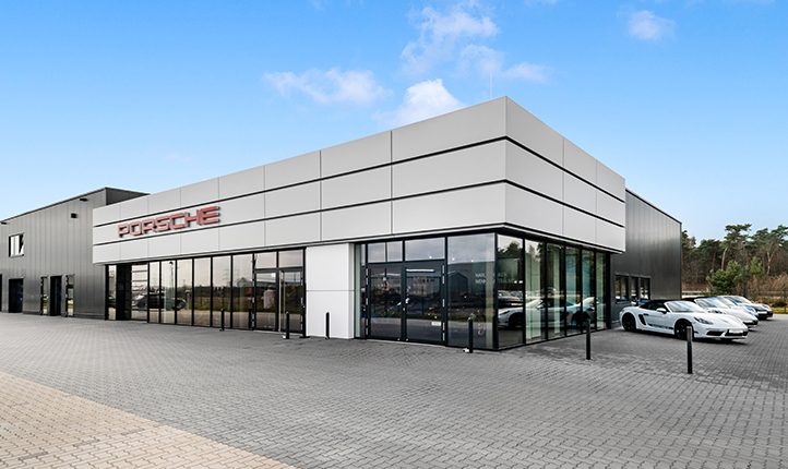 Fassade des Porsche Zentrum Emsbüren. Rechts parken Fahrzeuge. 
