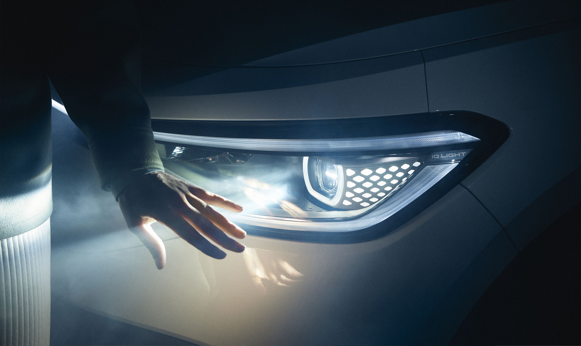 Nahaufnahme: Ein Scheinwerfer wirft Licht ins dunkle, davor ist eine Hand zu sehen.